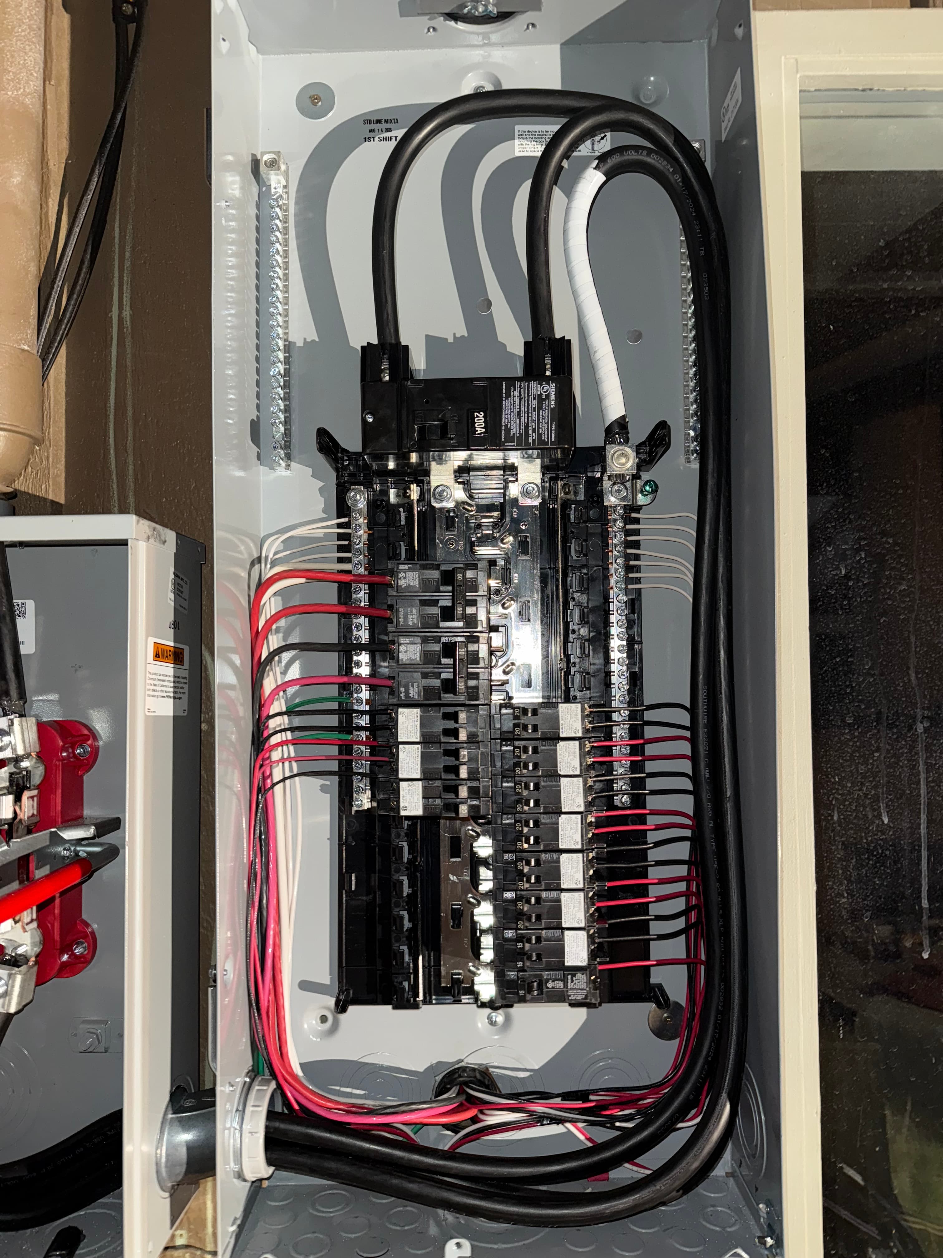 Open electrical panel box showing a main 200A breaker and multiple colored circuit wires.
